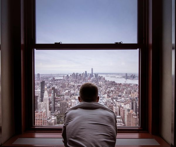 Man stretching by a large window overlooking a city skyline.
